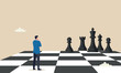 © YEASIN - Decision making leadership in business strategy concept, brave miniature figure businessman thinking and standing on chessboard looking at black chess enemy in far background