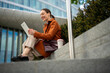 © Jelena - Woman smiling using digital tablet outdoors in city