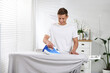 © New Africa - Man ironing curtain on board at home