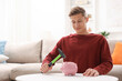 © New Africa - Man breaking piggy bank with hammer at white table indoors, space for text