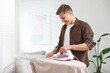 © New Africa - Man ironing curtain on board at home
