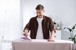 © New Africa - Man ironing curtain on board at home