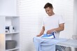 © New Africa - Man ironing shirt on board at home