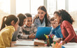 © Prostock-studio - Smiling Female Teacher Engaging With Group Of Six Students Including Boys And Girls During Learning Session, Collaborating And Sharing Ideas In Bright Classroom Environment. Educational Concept