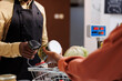 © DC Studio - Male seller scans products with a reusable scanner, promoting a sustainable, zero-waste shopping experience. Close-up image of two african american persons at the checkout counter, grasping a glass