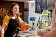 © DC Studio - Cheerful woman at checkout counter in zero waste shop selling healthy lentils in jar to customer with green living lifestyle. Client buys food in local neighborhood store from smiling vendor