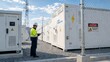 © Jafree - Electrical engineer wearing hard hat using digital tablet to inspect large battery energy storage system at wind farm power plant. Renewable energy infrastructure maintenance