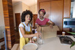 © wavebreak3 - Diverse female friends unpacking kitchen island with cardboard box, vase, plates, coffee cups
