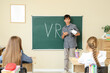 © Pixel-Shot - Teenage boy with VR glasses talking during lesson in classroom