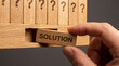 © ahmad - Hand pulling 'SOLUTION' block from row of question marks, problem-solving concept