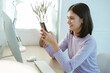 © Aphisara - The young woman glanced at her phone, checking the meeting agenda on her smartphone and making notes in her calendar to plan her upcoming tasks in her office workspace.