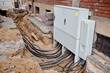 © beautiful-photo.de - Outdoor street cabinet connected to underground fiber optic internet and power utility cables at an urban construction site.