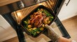 © RestuAry - Roasted chicken and vegetables in a baking dish being removed from the oven with a mitt.