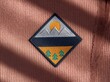 © HooSv - Macro close-up of a diamond embroidered patch with a nature mountain landscape on pink ribbed fabric. A highly detailed realistic apparel mockup.
