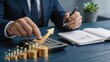 © Jieun - Businessman analyzing financial growth chart with rising arrow and stacks of gold coins on calculator for investment profit planning