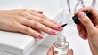 © Wei - Close-up of manicurist applying clear top coat to client's pink polished nails during professional beauty treatment session in spa or salon setting