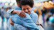 © Nataliya - Two anonymous people sharing a warm embrace at an airport terminal, heartfelt greeting or farewell concept, faceless, defocused busy background, with copy space