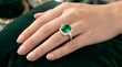 © Casandra - Woman's hand with emerald engagement ring closeup