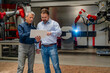 © BusinessClass by W61 - Engineers using tablet near industrial welding robot in factory