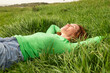 © VISTA by Westend61 - Happy woman lying in green grass relaxing in a meadow in Spain
