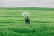 © VISTA by Westend61 - Businesswoman standing in a green wheat field with a transparent umbrella