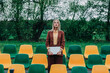 © VISTA by Westend61 - Businesswoman holding laptop by empty stadium seats outdoors