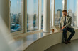 © BusinessClass by W61 - Businessman working on laptop sitting on office windowsill