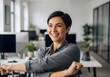 © dody - A professional woman stretching and smiling while working in a bright, modern office environment