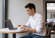 © Outsiderzone - Entrepreneur checking stock market graphs in modern cafe