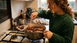 © Felippe Lopes - Woman stirring mulled wine with oranges and cinnamon sticks in a pot on a stove in a cozy kitchen