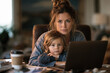 © NTGUILTY - Mother works on a laptop while holding her child in a home office setting