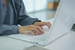 © Alisa siangjam - A person types on a white laptop keyboard while sitting at a desk.