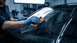 © Mahmuda - professional car window tinting installation | automotive windshield protective film application | technician using squeegee for window tint | car window tinting service in workshop