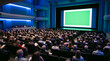 © dotmagic - A large audience sits in a dimly lit auditorium watching a presentation on a green screen