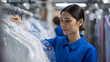 © photo for everything - Diligent young woman in blue uniform works at a bustling dry cleaner or laundry facility, organize clean clothing on racks, professional atmosphere