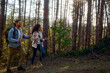 © DusanJelicic - Happy couple hiking uphill through sunlit forest with backpacks and trekking poles, smiling and enjoying an active outdoor adventure together on a leafy trail