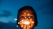 © Hanaro - A young boy with wide eyes looking at a bright sparkler held close to his face in the dark.