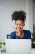 © Tj - Young smiling African American woman with pencil in hand watching content on laptop, studying online, learning new skills, working remotely or consulting an entrepreneurship project from home