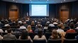 © Yassine - Professional speaker presenting future trends and innovations to a diverse audience in a modern conference hall, captured from the rear.
