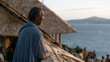 © forenna - Fishing village elder watching as satellite internet installation crew mounts equipment on community hall rooftop, children gathering curiously below, remote coastal community