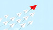 © Dadangurip - Red paper airplane leads a flock of white paper planes in formation, symbolizing leadership and teamwork against a blue sky