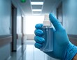 © Asik - Hand in glove holding a spray bottle in a brightly lit hallway