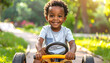 © Puput - Happy young african american boy with a big smile riding a toy car outdoors on a sunny day