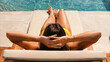 © ArtFocus Studio - Woman relaxing and sunbathing by a pool, high angle view from behind