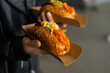 © ADDICTIVE STOCK - Street food hot dog with carrot slaw and mustard in hand