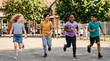 © Victoriia - Group of children run together during recess in an elementary school playground enjoying their time with diverse friends