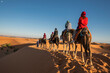 © Cavan Images - group of friends enjoying a camel ride in the Sahara