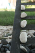 © abror - Smooth white pebbles balanced on rustic metal grate with garden stones and lush green grass