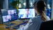 © mr_marcom - Female doctor in white coat reviewing patient records on dual monitors while video calling a colleague in a dark modern medical office during a late telemedicine shift