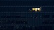 © xiden - A modern glass office building facade photographed from outside at night showing one single illuminated room amidst dark windows
